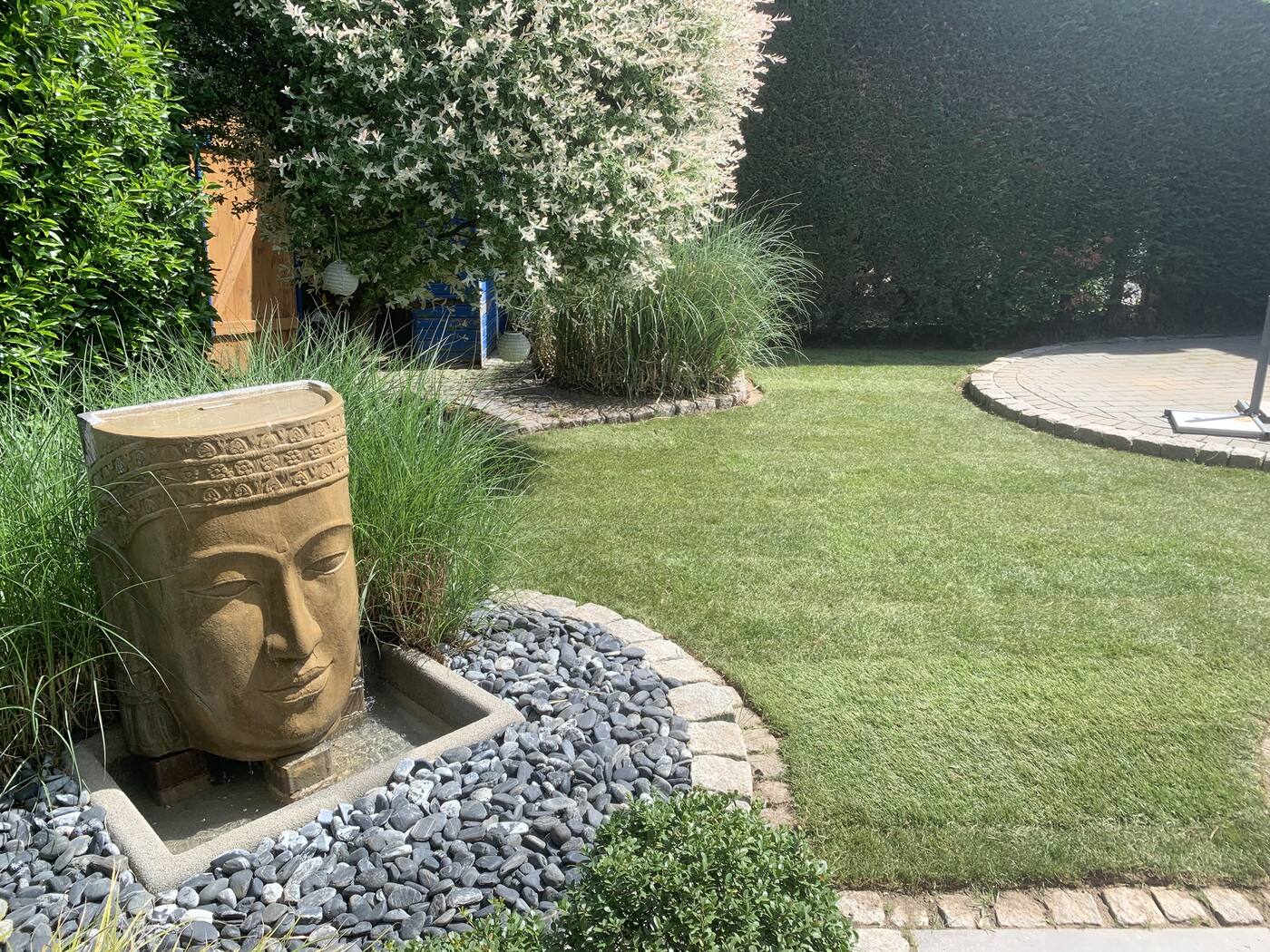Garten mit Brunnen, Kieselbeet und frischem Rasen