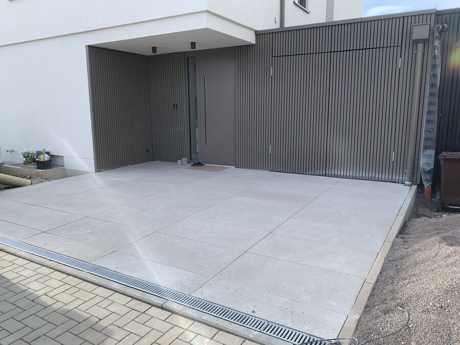 Eingangsbereich mit hellen Großformatplatten und Lamellenfassade
