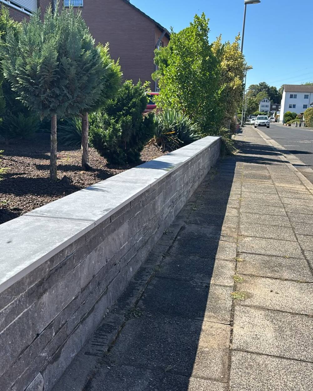 Natursteinmauer mit Abdeckplatte an einem Vorgarten