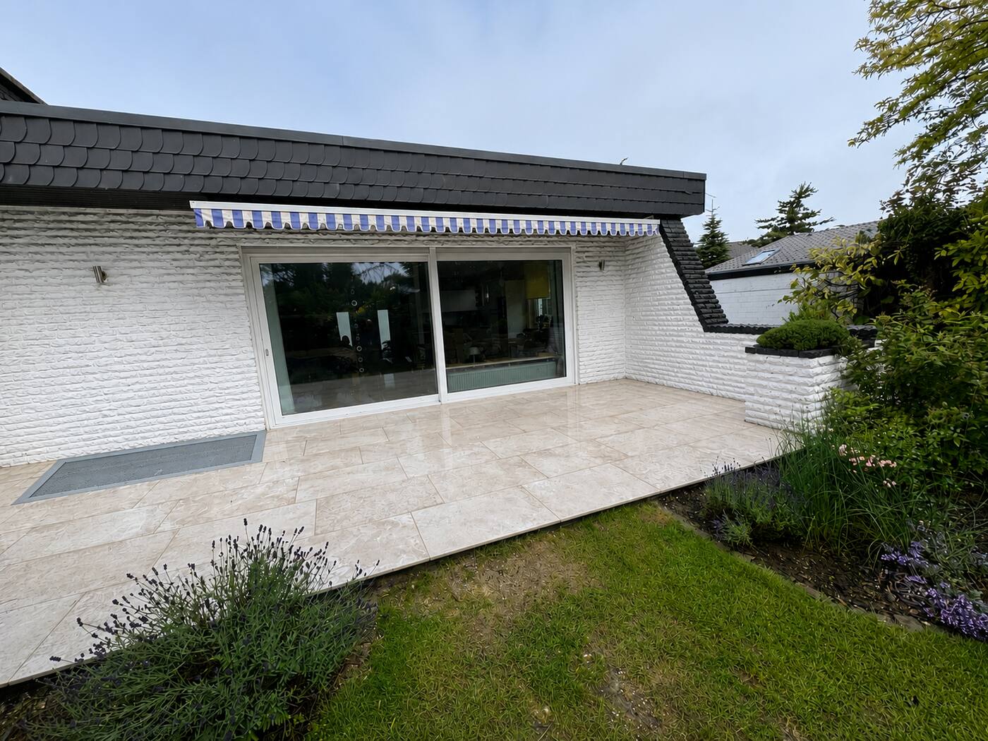Fertige Terrasse aus hellen Keramikplatten am Haus