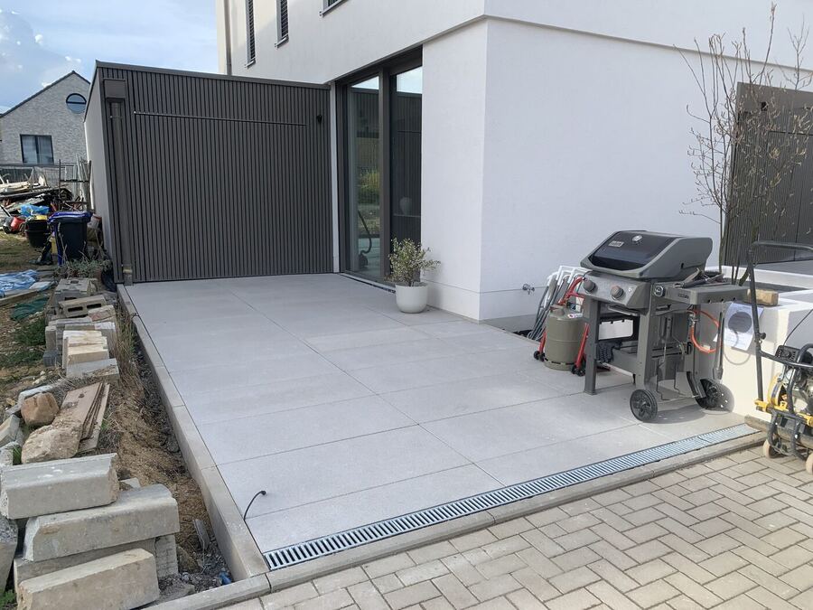 Helle Großformat-Terrasse mit Entwässerungsrinne an einem Neubau